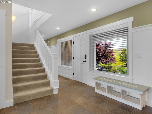 entrance foyer featuring a decorative wall, stairs, stone tile floors, recessed lighting, and a wainscoted wall
