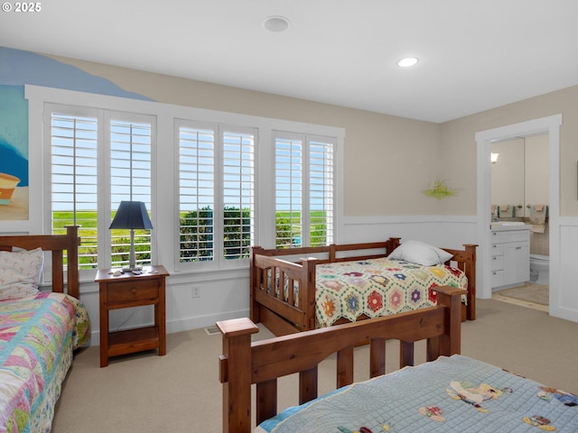carpeted bedroom featuring wainscoting, recessed lighting, and connected bathroom