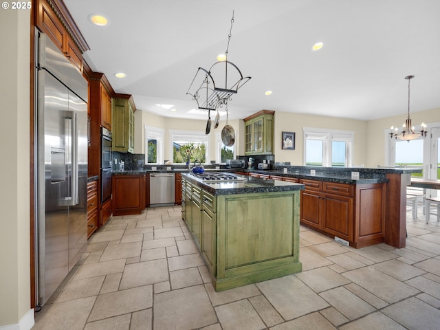 kitchen with appliances with stainless steel finishes, a chandelier, tasteful backsplash, a center island, and healthy amount of natural light