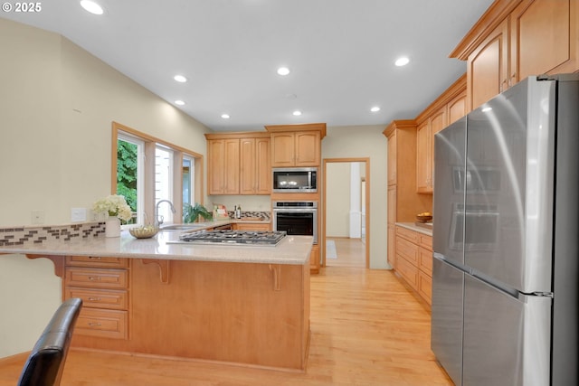 2038 Morning View Dr, Eugene, OR 97405 - kitchen featuring appliances with stainless steel finishes, a peninsula, light wood-style floors, a kitchen bar, and light brown cabinets