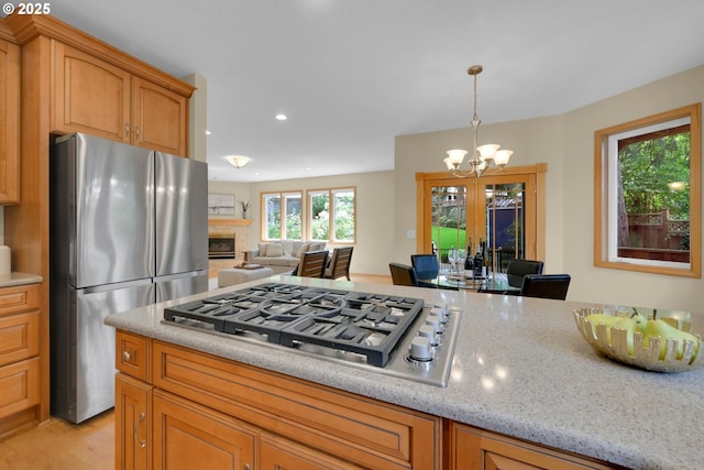 2038 Morning View Dr, Eugene, OR 97405 - kitchen with appliances with stainless steel finishes, a chandelier, light stone counters, a fireplace, and open floor plan