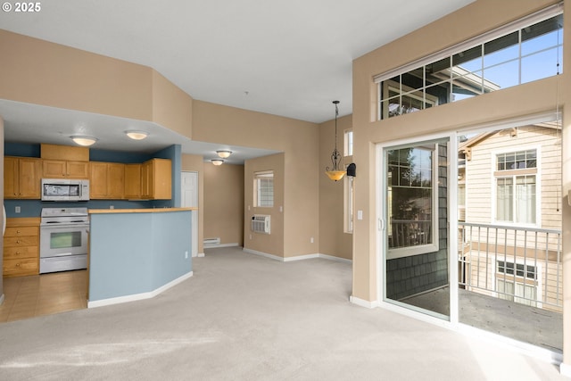 kitchen with white appliances, hanging light fixtures, a wall mounted AC, and light colored carpet