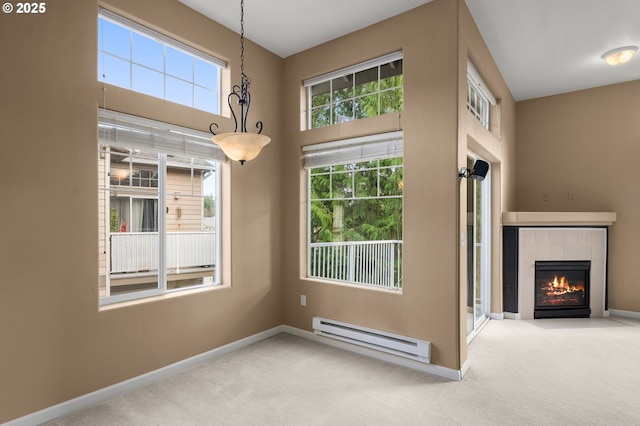 unfurnished living room with a tiled fireplace, a baseboard heating unit, and carpet