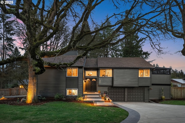 view of front of property featuring a garage, a front yard, concrete driveway, and fence