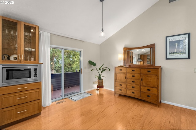 interior space featuring light wood finished floors, baseboards, visible vents, and high vaulted ceiling