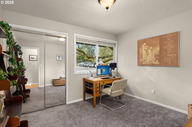 carpeted office space featuring baseboards and a textured ceiling