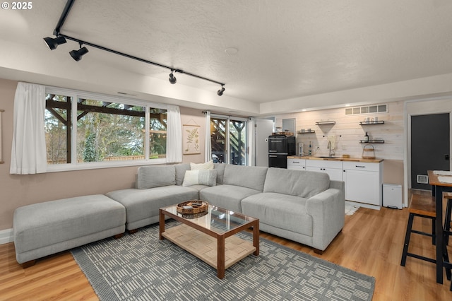 living room with light wood finished floors, visible vents, and a textured ceiling