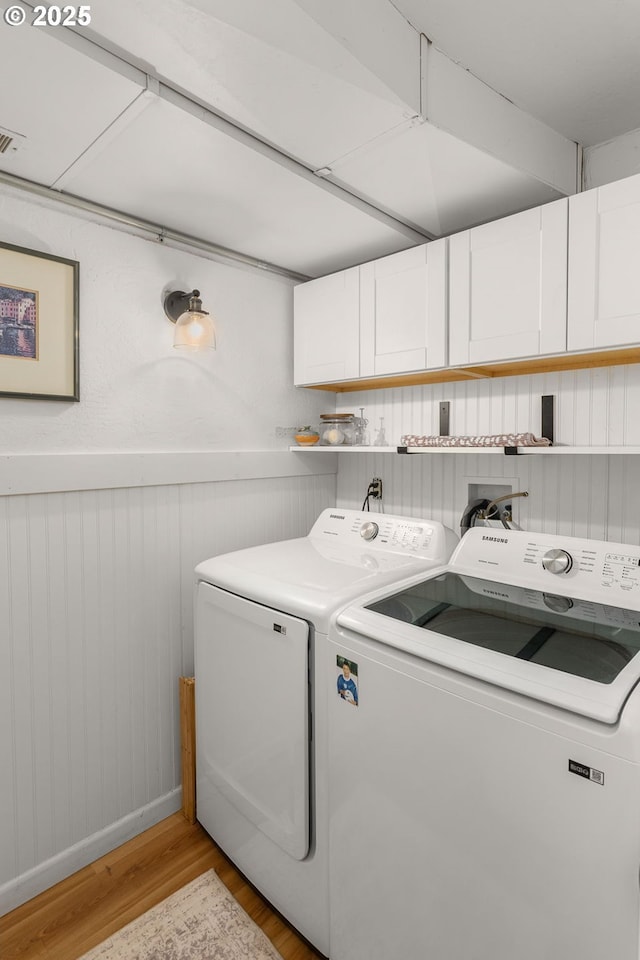 clothes washing area featuring cabinet space, visible vents, wainscoting, independent washer and dryer, and light wood-type flooring