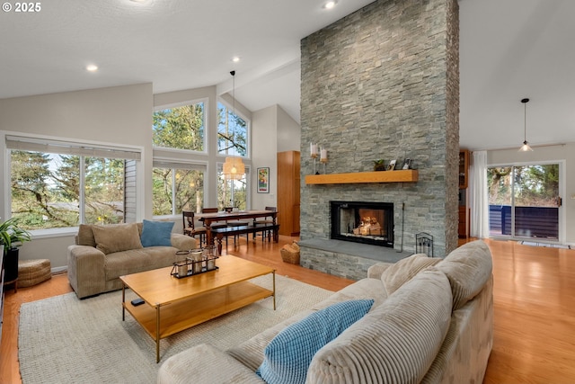 living room featuring plenty of natural light, high vaulted ceiling, a fireplace, and wood finished floors