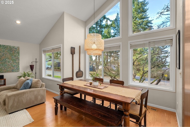 dining room with light wood-style floors, recessed lighting, high vaulted ceiling, and baseboards