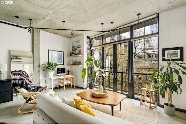 living room with floor to ceiling windows, french doors, baseboards, and concrete floors