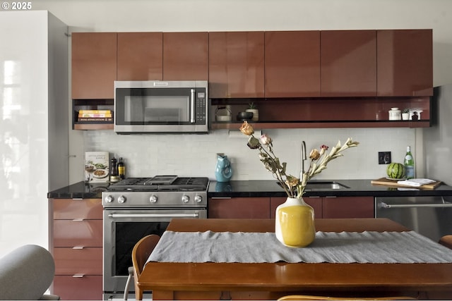 kitchen with dark countertops, open shelves, decorative backsplash, stainless steel appliances, and a sink