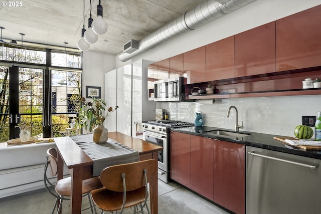 kitchen featuring tasteful backsplash, finished concrete floors, hanging light fixtures, stainless steel appliances, and a sink