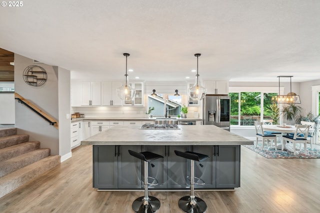 kitchen featuring appliances with stainless steel finishes, a kitchen island, white cabinetry, light countertops, and recessed lighting