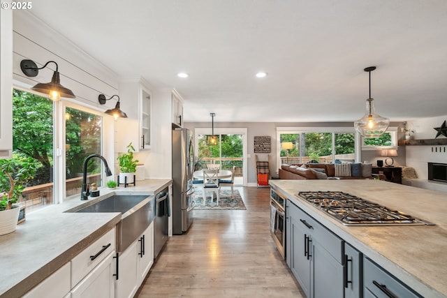 kitchen with a sink, appliances with stainless steel finishes, open floor plan, pendant lighting, and recessed lighting