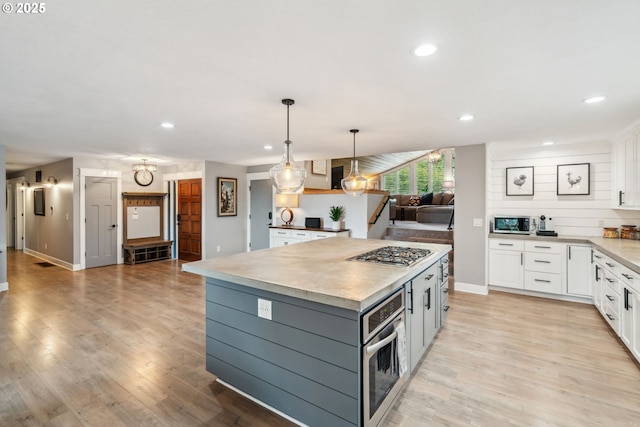 kitchen featuring stainless steel appliances, white cabinetry, recessed lighting, a center island, and light wood-style floors
