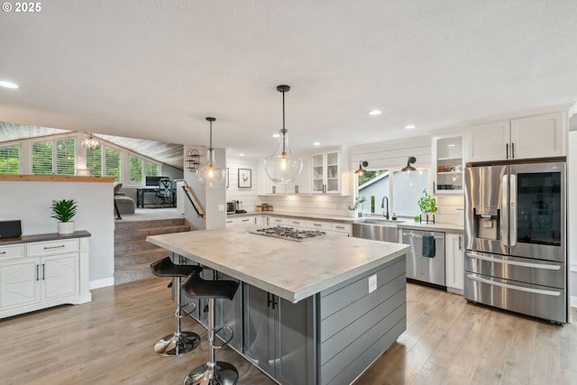 kitchen with appliances with stainless steel finishes, a sink, light wood-style floors, light countertops, and white cabinets