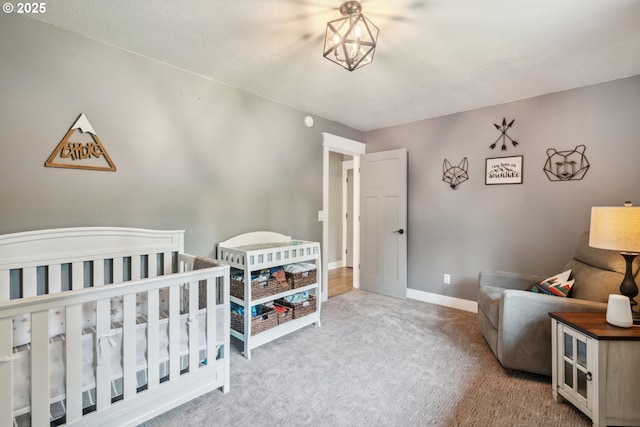 carpeted bedroom with a nursery area and baseboards