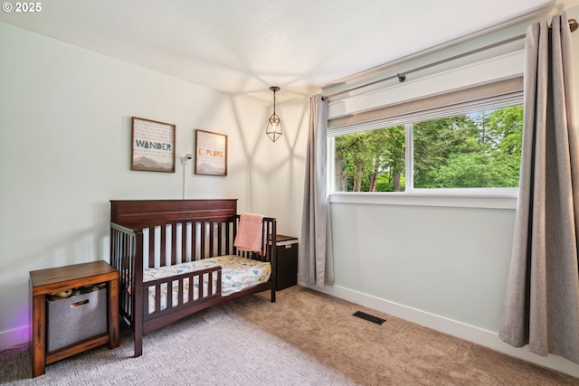 bedroom featuring carpet floors, a nursery area, and baseboards