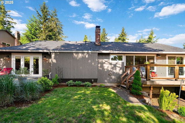 back of house with a deck, a chimney, a lawn, and roof with shingles