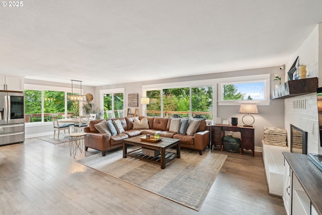 living area with wood-type flooring, healthy amount of natural light, baseboards, and a brick fireplace