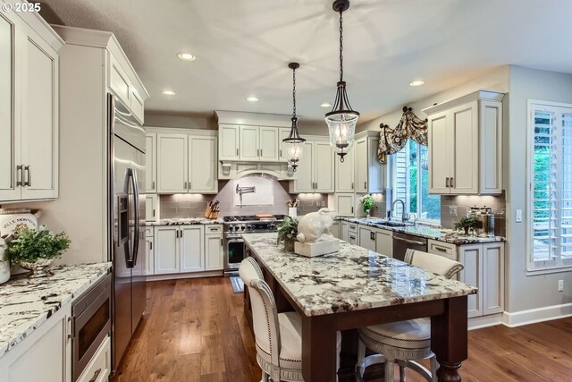 kitchen with tasteful backsplash, pendant lighting, stainless steel dishwasher, sink, and dark wood-type flooring