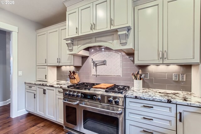 kitchen featuring premium appliances, tasteful backsplash, light stone countertops, pendant lighting, and a center island