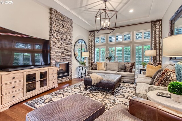 living room featuring dark wood-type flooring, a fireplace, and an inviting chandelier