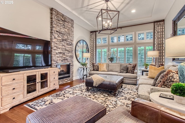 living room featuring dark wood-type flooring, an inviting chandelier, a fireplace, and a towering ceiling