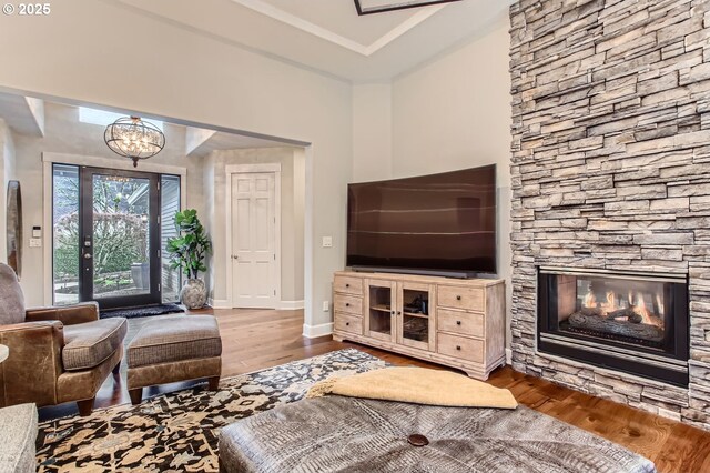 living room with hardwood / wood-style floors, a stone fireplace, and a notable chandelier