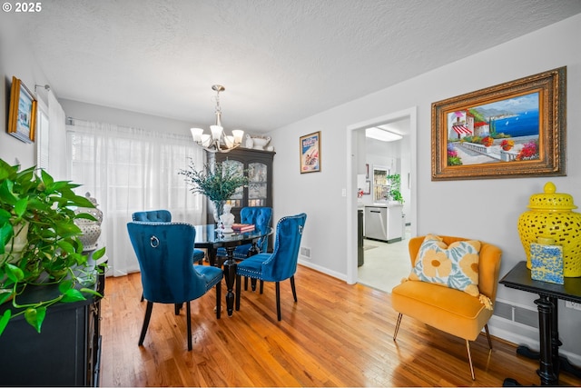 dining room featuring light hardwood / wood-style flooring, a textured ceiling, and a chandelier