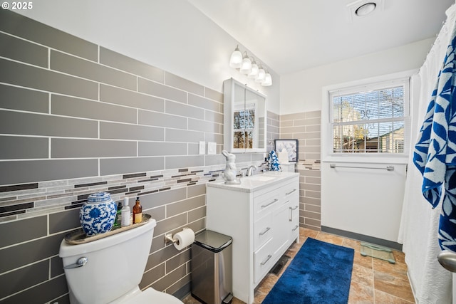 bathroom featuring vanity, tile walls, and toilet