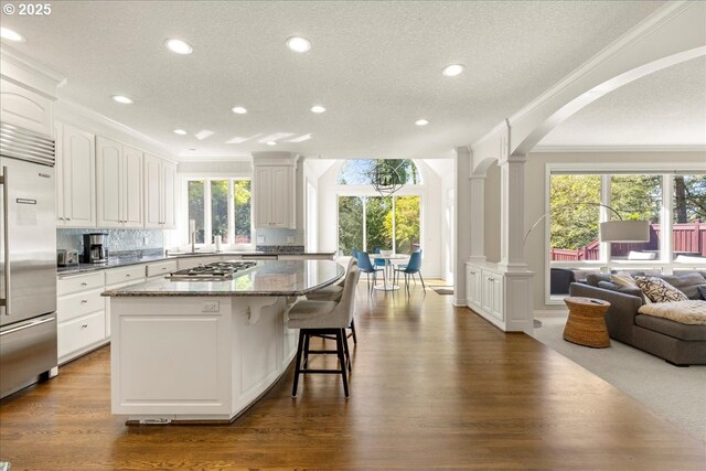 6230 SW Patton Rd, Portland, OR 97221 - kitchen featuring stainless steel appliances, ornamental molding, ornate columns, arched walkways, and dark stone countertops