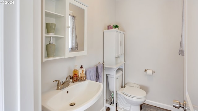 bathroom featuring a sink, baseboards, and toilet