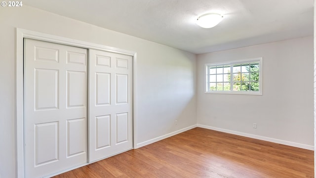 unfurnished bedroom with a closet, light wood-style flooring, and baseboards