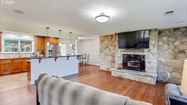 living room featuring a textured ceiling, visible vents, light wood-style flooring, and a fireplace