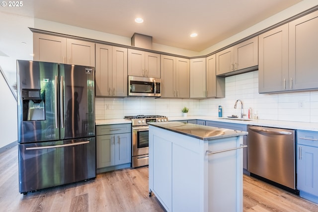 2904 SE 87th Ave, Portland, OR 97266 - kitchen with stainless steel appliances, a sink, light wood finished floors, a kitchen island, and decorative backsplash