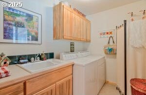 laundry area with cabinet space, washer and dryer, and a sink