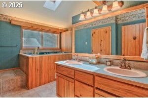 full bath featuring double vanity, a skylight, and a sink