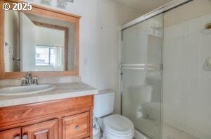 full bathroom featuring vanity, a shower stall, and toilet