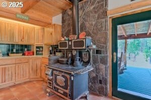 kitchen with light brown cabinets, wood ceiling, and a wood stove