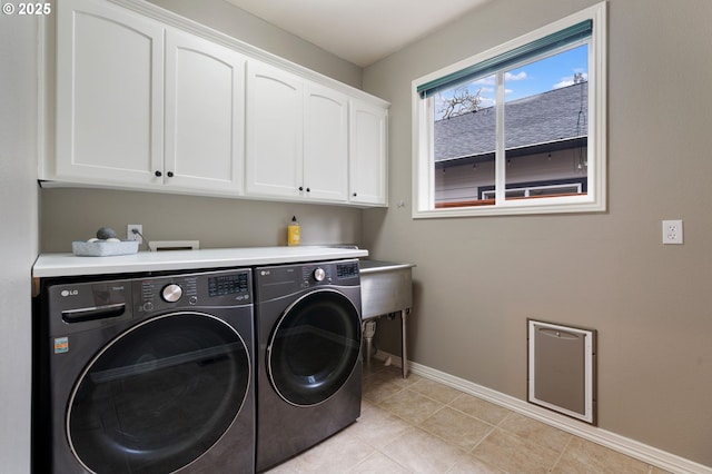 washroom with light tile patterned floors, washer and dryer, and cabinets