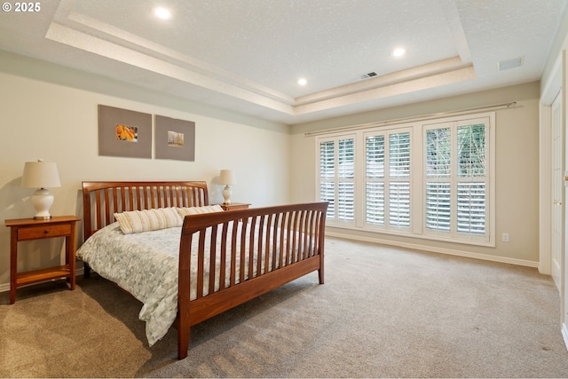 carpeted bedroom featuring a tray ceiling and a textured ceiling