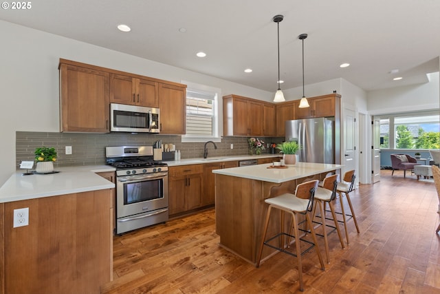 29250 SW Costa Cir E, Wilsonville, OR 97070 - kitchen featuring appliances with stainless steel finishes, a sink, a kitchen breakfast bar, light wood-style floors, and brown cabinets