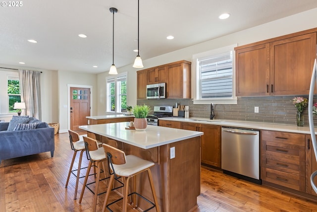 29250 SW Costa Cir E, Wilsonville, OR 97070 - kitchen featuring stainless steel appliances, a sink, brown cabinetry, light wood finished floors, and recessed lighting