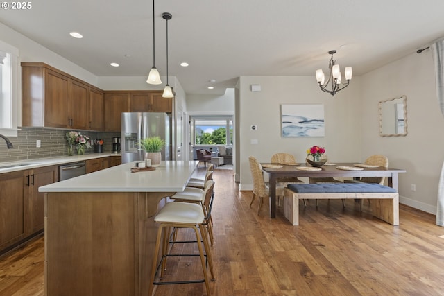 29250 SW Costa Cir E, Wilsonville, OR 97070 - kitchen featuring appliances with stainless steel finishes, baseboards, a sink, decorative backsplash, and wood finished floors