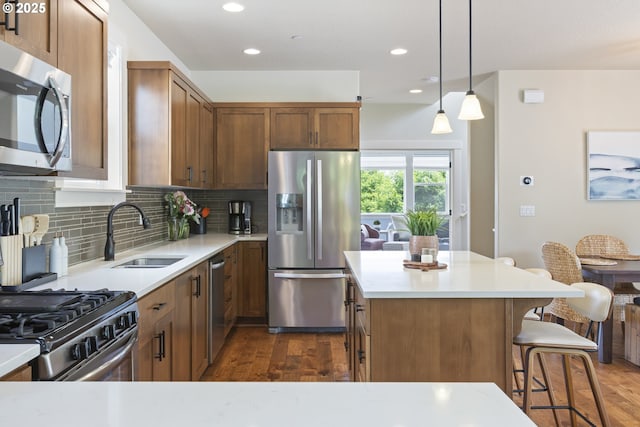 29250 SW Costa Cir E, Wilsonville, OR 97070 - kitchen with appliances with stainless steel finishes, a sink, dark wood-type flooring, a breakfast bar area, and backsplash