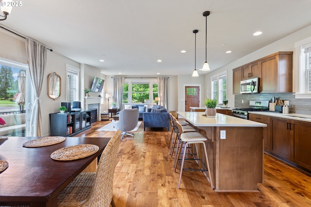 29250 SW Costa Cir E, Wilsonville, OR 97070 - kitchen with stainless steel appliances, open floor plan, brown cabinets, a center island, and light wood finished floors
