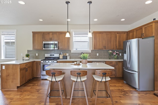 29250 SW Costa Cir E, Wilsonville, OR 97070 - kitchen featuring stainless steel appliances, plenty of natural light, brown cabinetry, a kitchen bar, and recessed lighting