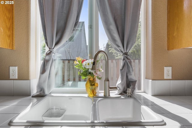 room details featuring a sink, tile countertops, and a textured wall